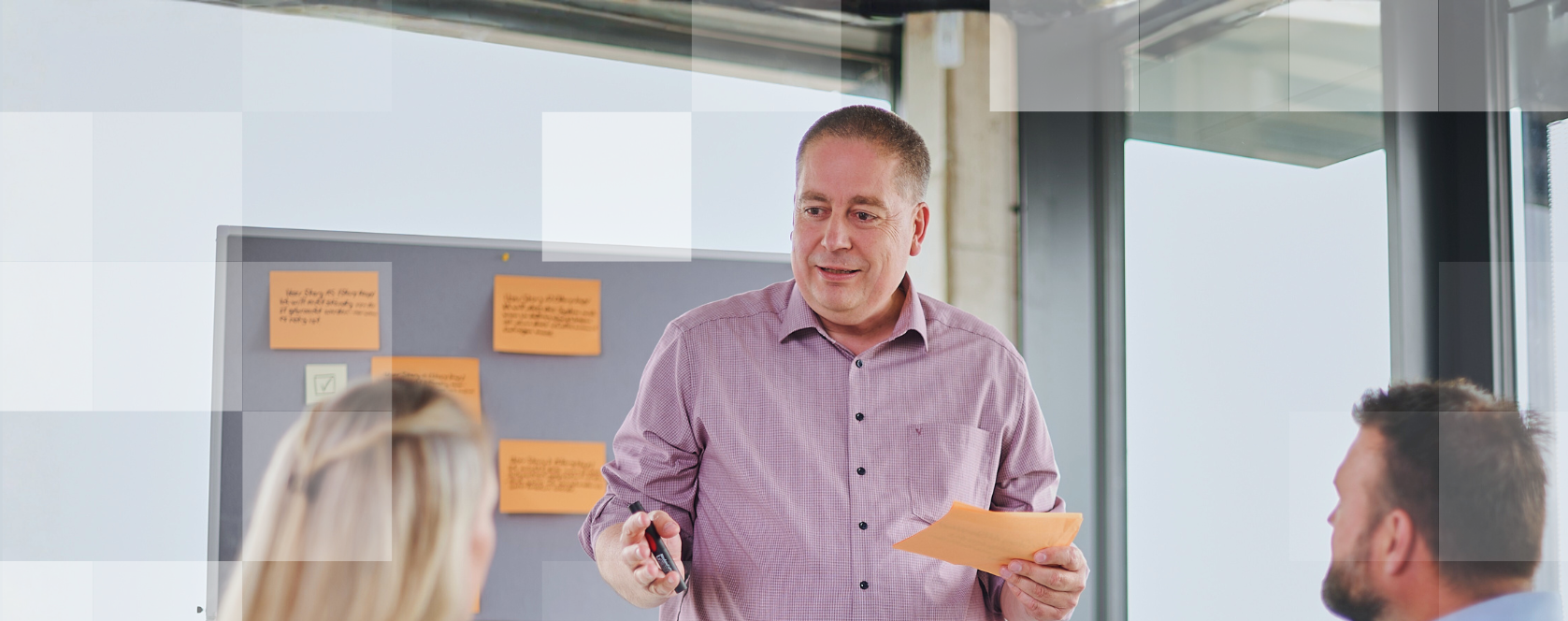 Ein MEGLA Mitarbeiter hält eine Schulung, zwei Personen hören ihm zu